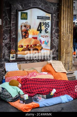 Un homme sans abri dormant à l'extérieur d'un restaurant McDonalds, à l'angle de la Calle de la Montera et de la Gran via, Madrid, Espagne. Banque D'Images