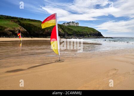 Drapeaux de sauveteurs marquant la zone de baignade sécuritaire à Poldhu Cove, péninsule de Lizard, Cornwall, Royaume-Uni Banque D'Images