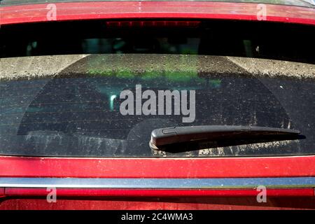 Lunette arrière rouge sale, lunette arrière avec essuie-glace recouvert de poussière après la pluie, gros plan. Banque D'Images