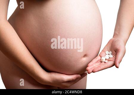 ventre d'une femme enceinte tenant une main sous le ventre dans l'autre main tient un rond pilules blanches pour les soins de santé, gros plan du corps humain no Banque D'Images