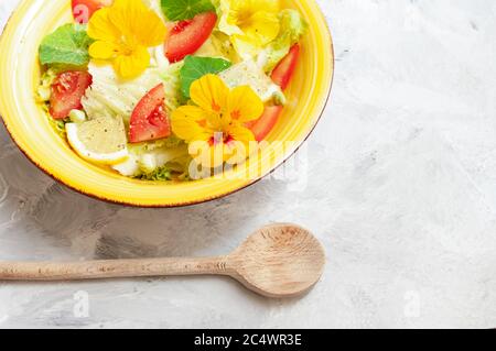Salade d'été, avec fleurs jaune nasturtium, tomates, citrons. Cuisine végétarienne, saine. Cuisine colorée. Copier l'espace. Banque D'Images