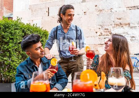 Des amis qui boivent un cocktail coloré au bar en plein air - Nouveau concept de vie normale avec des gens heureux qui toastent des boissons à l'extérieur Banque D'Images