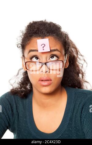 portrait d'une jeune femme à peau sombre confuse avec un point d'interrogation sur son front sur fond blanc Banque D'Images