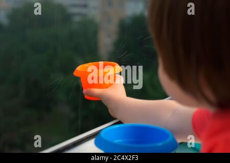 Enfant attrapant des gouttes de pluie. Concept de séjour à la maison. Jour de pluie, attrapant les gouttes d'eau avec l'assiette. Bonne enfance. Concept Montessori. Concept d'écologie Banque D'Images