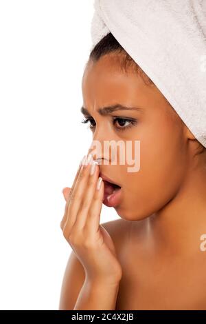 portrait d'une jeune femme à la peau sombre qui vérifie son souffle sur fond blanc Banque D'Images