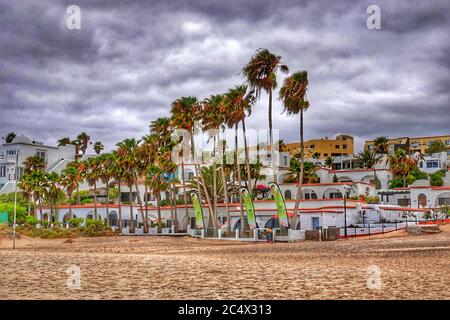 Fuerteventura, îles Canaries - 19 juillet 2019 : journée nuageux à la plage de Costa Calma. Costa Calma plage avec des nuages, des palmiers et un quartier résidentiel. Banque D'Images