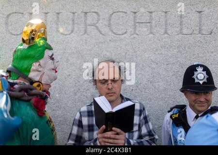 Un homme lit un livre devant une statue de Winston Churchill lors d'une démonstration de Black Lives Matter, Parliament Square, Londres, 21 juin 2020 Banque D'Images