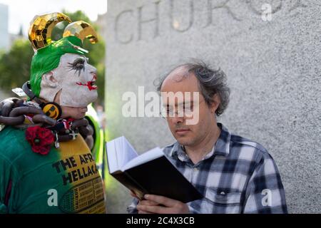 Un homme lit un livre devant une statue de Winston Churchill lors d'une démonstration de Black Lives Matter, Parliament Square, Londres, 21 juin 2020 Banque D'Images