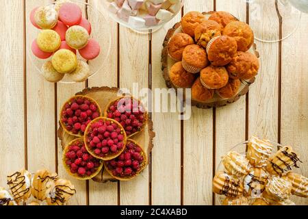 Vue plate de savoureux desserts sur une table en bois. Muffins, macarons, tartes de framboises et biscuits Banque D'Images