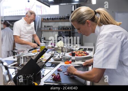 Chef cuisinier femme coupant des oignons dans la cuisine du restaurant Banque D'Images