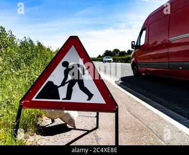 Minibus rouge passant devant un panneau d'avertissement, Écosse. Banque D'Images