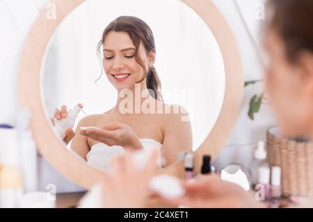 Bonne femme attrayante utilisant le toner visage après la douche Banque D'Images