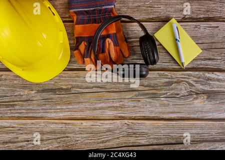 Industrie travailleurs de protection vêtements de travail norme de sécurité construction sécurité casque antibruit cuir dans casque de sécurité gants de protection notes papier sur table en bois vue du dessus Banque D'Images