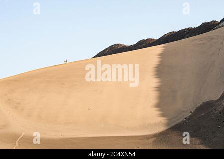 Homme vu d'une distance à pied sur une grande dune dans le désert péruvien. CASMA, Département d'Ancash, Pérou. Banque D'Images