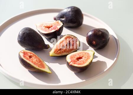 Image horizontale des figues en plaque céramique blanche filmée dans des conditions d'éclairage difficiles. Banque D'Images