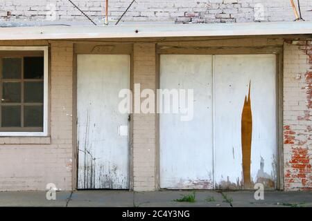 un magasin abandonné avec façade en briques peintes blanches et auvent endommagé Banque D'Images
