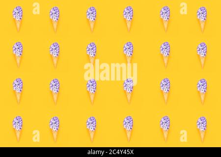 Motif sans couture. Cône de glace gaufré avec fleur de jacinthe violette sur fond jaune. Concept de ressort. Espace de copie, vue de dessus. Banque D'Images