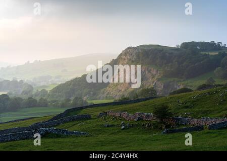 La lumière brumeuse de l'après-midi crée des couches dans le paysage du parc national de Yorkshire Dales, au-dessus de Langcliffe, lors d'une journée humide et orageux. Banque D'Images