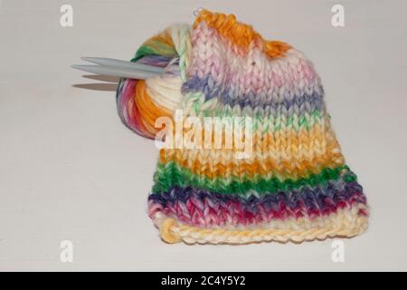 balle de laine avec aiguilles à tricoter; écharpe tricotée en couture de stockinette avec fil de laine dégradé de couleur; Banque D'Images