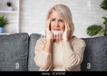Femme âgée souffrant de maux de tête ou de dépression grimaquant dans la douleur Banque D'Images