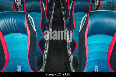 Image de l'intérieur d'un autobus de voyage vide avec rangées de sièges en tissu bleu et rouge et couloir long. Banque D'Images