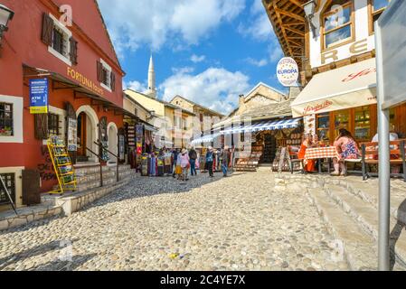 Les touristes achètent des cadeaux et des souvenirs tandis que les convives apprécient un café-terrasse sur les rues pavées de la vieille ville médiévale de Mostar, en Bosnie. Banque D'Images