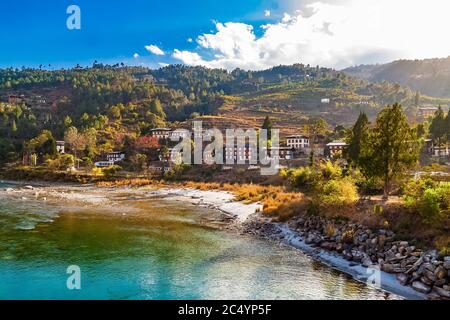 Le fleuve Mo Chhu par une belle journée ensoleillée, Punakha, Bhoutan. Vue du pont en bois en porte-à-faux près de Punakha Dzong à la rivière, maisons de la ville de Punakha et lui Banque D'Images