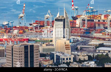 Haifa, Israël - octobre 2018: Vue du port de Haif? Et la tour de voile Beit HaMifras et les grues de port, les conteneurs de cargaison et les navires dans un soleil Banque D'Images