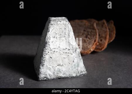 Une pyramide de fromage de chèvre recouverte de cendres avec des tranches de pain semées au levain Banque D'Images