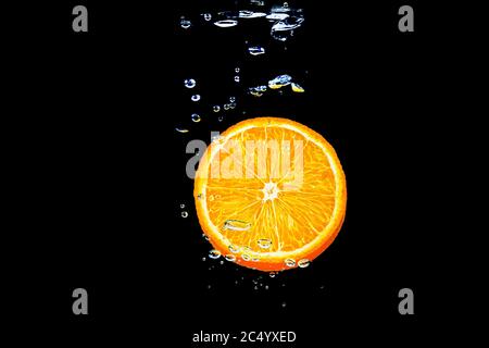 orange dans l'eau sur fond noir sous l'eau avec des bulles. Banque D'Images