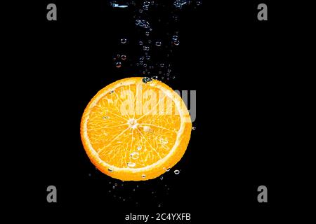 orange dans l'eau sur fond noir sous l'eau avec des bulles. Banque D'Images