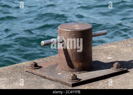 Un navire maritime rouillé amarre un cale ou un bollard sur un jetée au bord de l'eau Banque D'Images