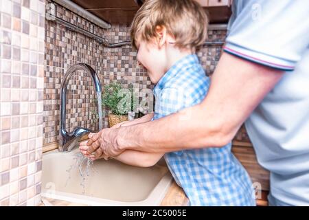 Son fils gai et son père se lavant les mains avec du savon et de l'eau dans la salle de bains. Concept de sécurité et d'hygiène pour les séjours d'homme et de petit garçon. Sélectionnez Banque D'Images