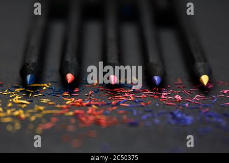 Crayons noirs, de couleur, sur fond noir, et copeaux des crayons. Concept de travail d'équipe Banque D'Images