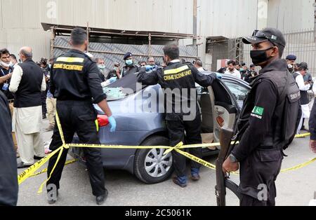 Des membres de l'unité de scène de crime de police enquêtent sur une voiture utilisée par des hommes armés présumés à l'entrée principale de la Bourse du Pakistan à Karachi le lundi 29 juin 2020. La police a déclaré que les quatre « terroristes » qui ont attaqué la très occupée Bourse du Pakistan (PSX) vers 10 heures lundi matin avaient été tués par des agents de sécurité, avec deux gardes de sécurité et un sous-inspecteur de police martyrisés en repoussant la tentative d'assaut le bâtiment le plus occupé de l'I.I. de Karachi Chundrigar Road, également connue sous le nom de Wall Street au Pakistan. Banque D'Images