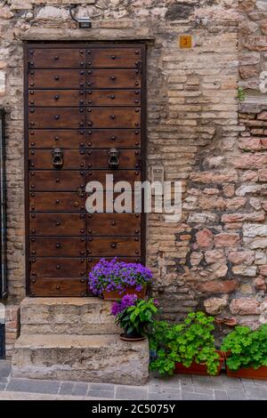 Scène de rue avec pots de fleurs sur les marches d'une porte d'une maison dans la ville historique d'Assise, dans la province de Pérouse dans la région de l'Ombrie en ITA Banque D'Images