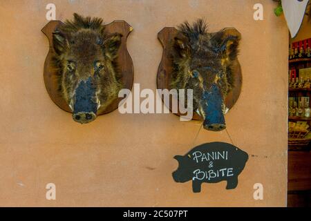 Scène de rue avec des têtes de sanglier sur un mur d'un boucherie dans la ville de Norcia dans la province de Pérouse dans le sud-est de l'Ombrie, Italie. Banque D'Images