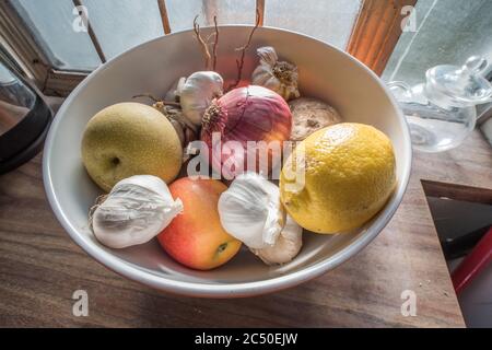 Une vie encore d'un bol de fruits et légumes mélangés assis sur un comptoir dans une cuisine. Banque D'Images