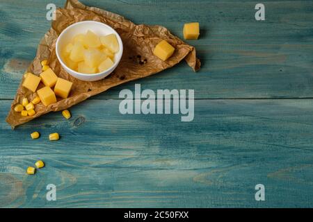 Bouquet de ananas et fromage coupé dans des dés sur fond bleu en bois Banque D'Images