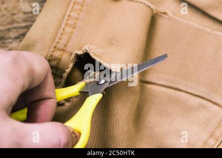 Une femme coupe une paire de ciseaux jaune à vieux jeans. Réparation et couture de vêtements. Sur mesure. Vue du dessus. Banque D'Images