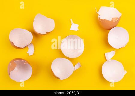 Vider les coquilles d'œufs brunes cassées sur fond jaune. Moitiés et pièces Banque D'Images