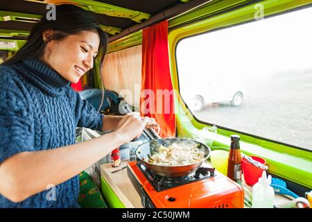 femme qui cuisine à l'intérieur d'une camionnette de camping à un endroit éloigné de Islande Banque D'Images