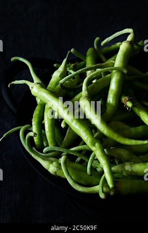 Vue de dessus des piments frais et verts dans l'obscurité. Banque D'Images