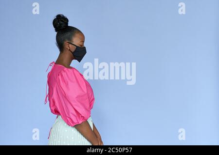 Jeune femme africaine portant un élégant masque de visage noir tendance isolé sur le lilas. Banque D'Images