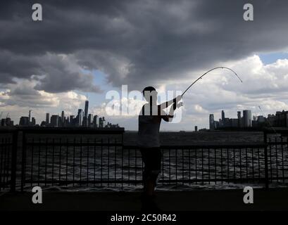 Hoboken, États-Unis. 29 juin 2020. Un homme va pêcher avec une vue sur One World Trade Center et les gratte-ciel de Manhattan avant un orage le lundi 29 juin 2020 à Hoboken, New Jersey. La ville de New York se prépare à entrer dans la phase 3 d'un plan de réouverture en quatre parties le 6 juillet après avoir été fermée pendant près de 4 mois en raison de la COVID-19. Photo de John Angelillo/UPI crédit: UPI/Alay Live News Banque D'Images