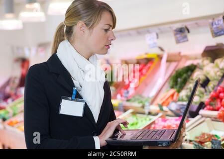 femme directrice utilisant un ordinateur portable dans un supermarché Banque D'Images