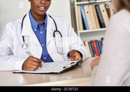 Femme africaine médecin consulter femme patient remplissant le formulaire médical à rendez-vous. Banque D'Images