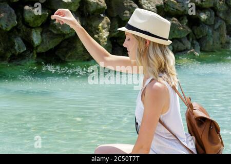 femme qui lance une pièce dans une fontaine Banque D'Images