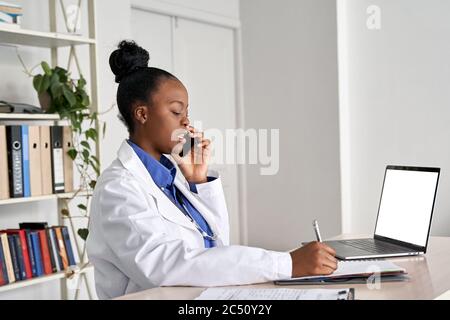Jeune femme africaine médecin médecin tenant le téléphone parlant sur mobile au travail. Banque D'Images