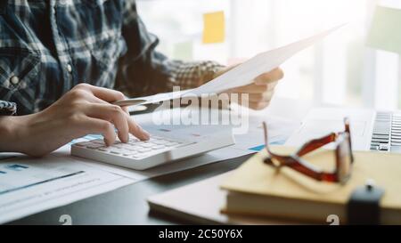Homme d'affaires proche utilisant une calculatrice et un ordinateur portable pour calculer le concept de la finance, de la fiscalité, de la comptabilité, des statistiques et de la recherche analytique Banque D'Images